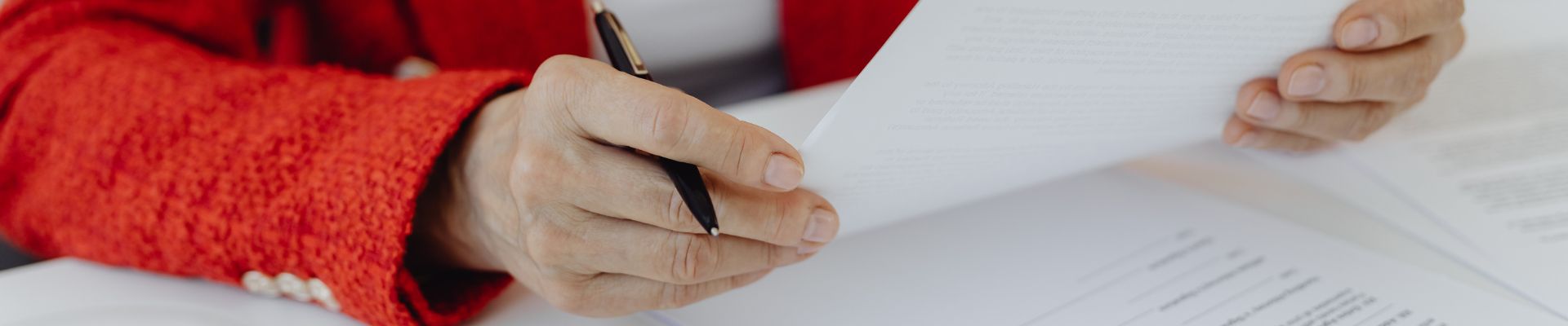 Older woman looking at terms and conditions with a pen in her hand.