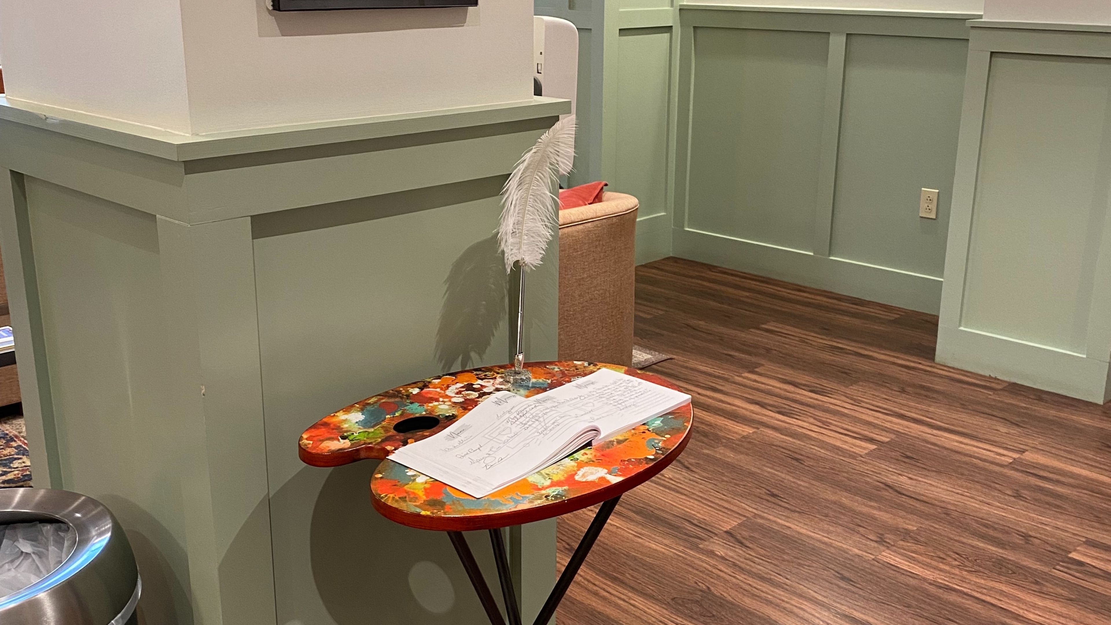 A small table with a notebook and feather decoration in a lobby area.