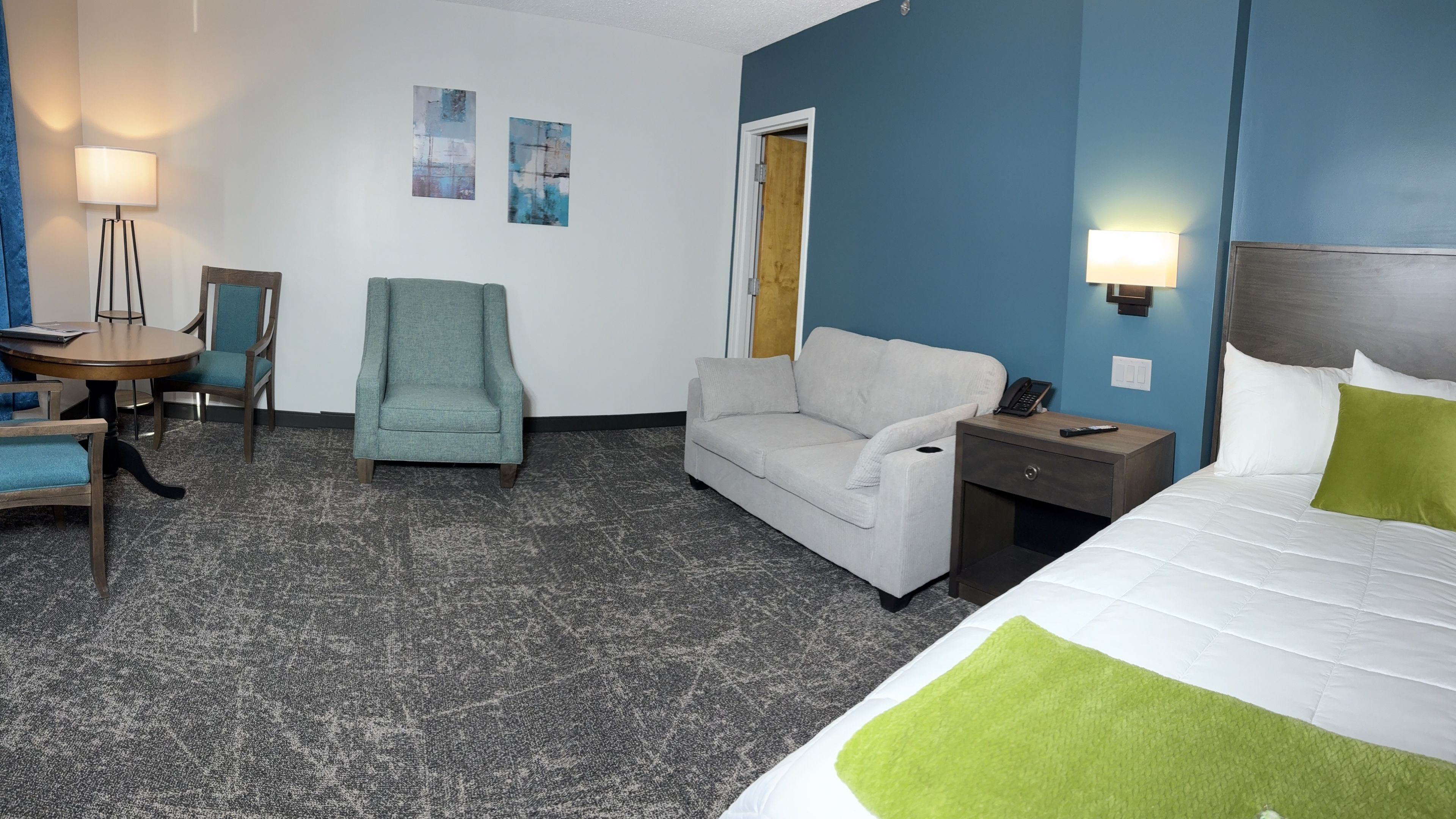 A hotel room with a bed, sofa, desk, and chair.