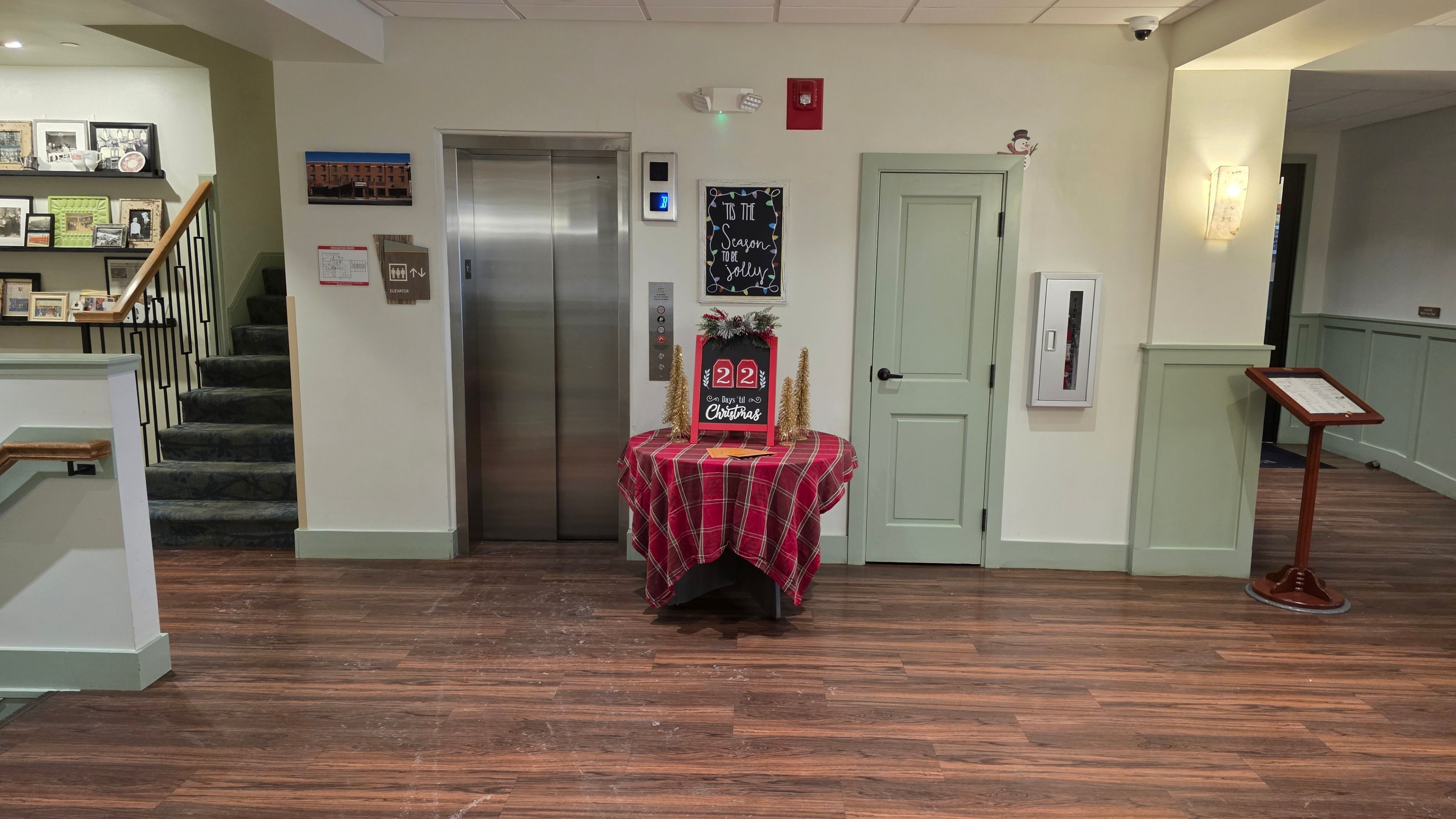 A hotel lobby with an elevator, staircase, and a decorated table.