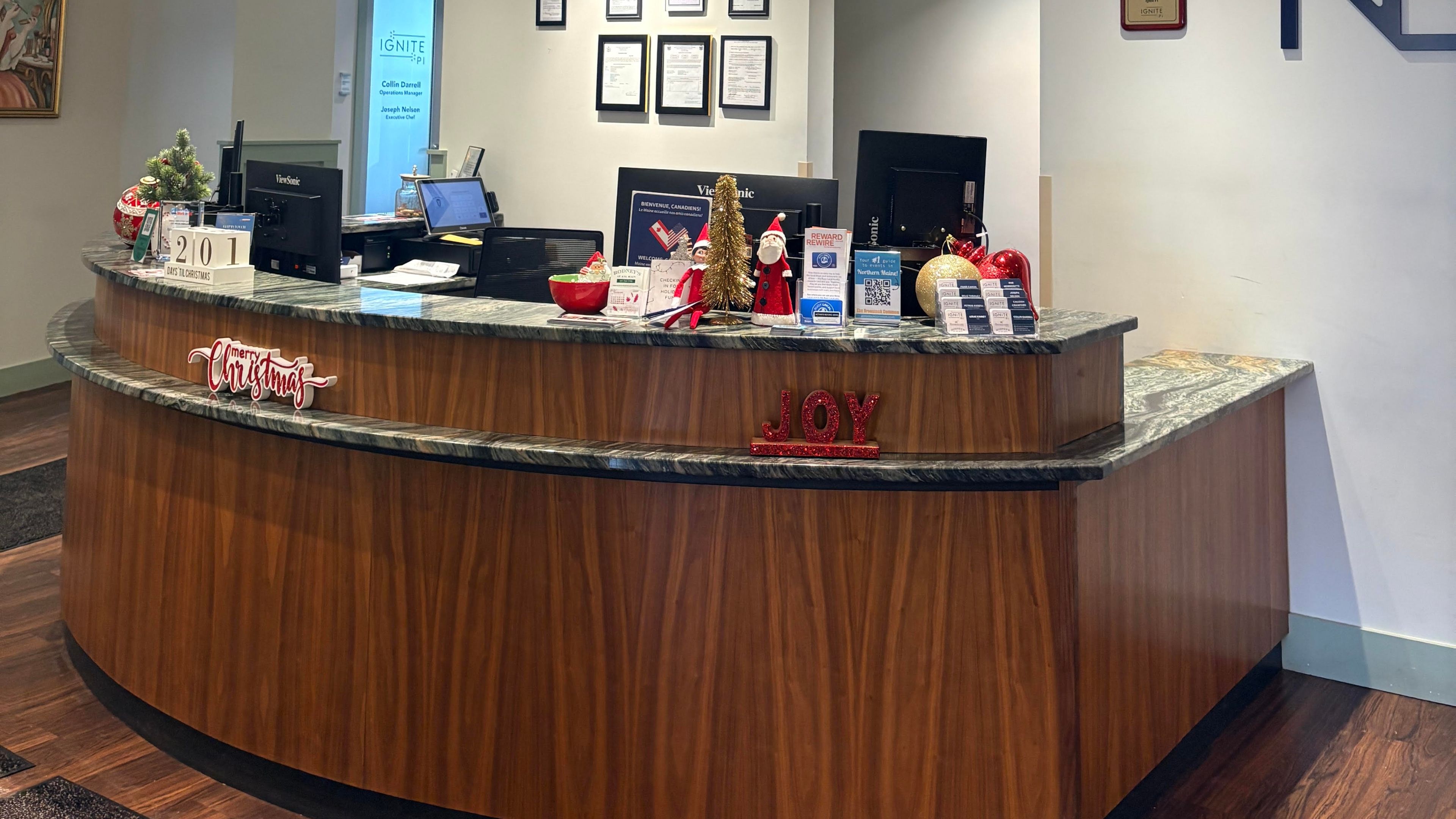 A curved reception desk with a marble countertop and wood paneling, decorated for Christmas.